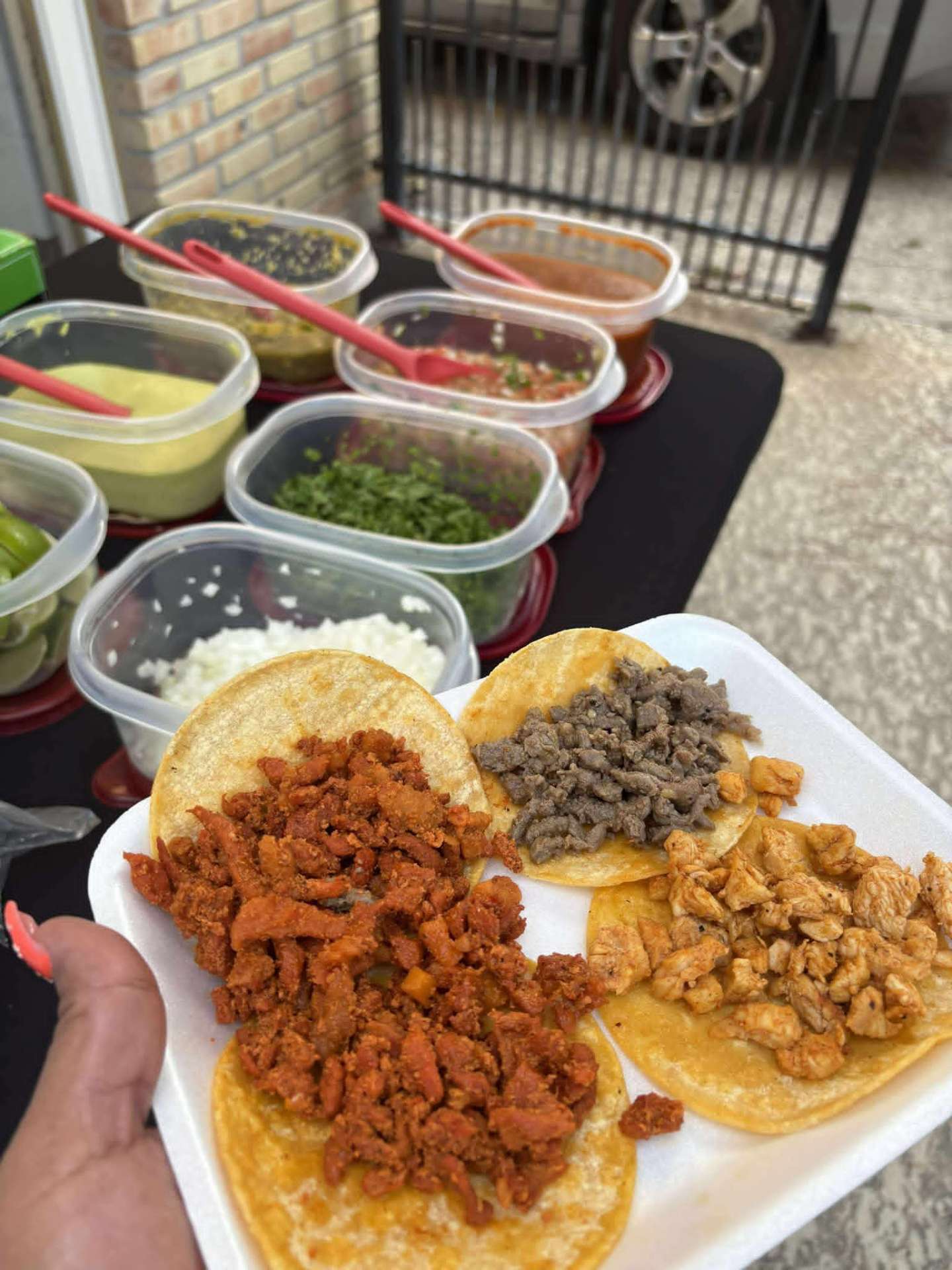 Plate of beef, chicken and al pastor tacos with salsas and toppings